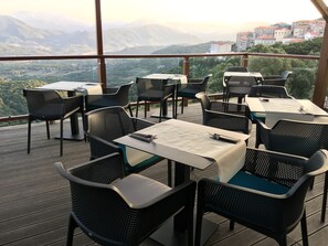 Zona d'esmorzar a l'aire lliure amb taules i cadires, amb vistes a un paisatge de muntanya.