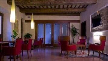 A room with red chairs, a wooden ceiling, and a TV mounted on the wall.