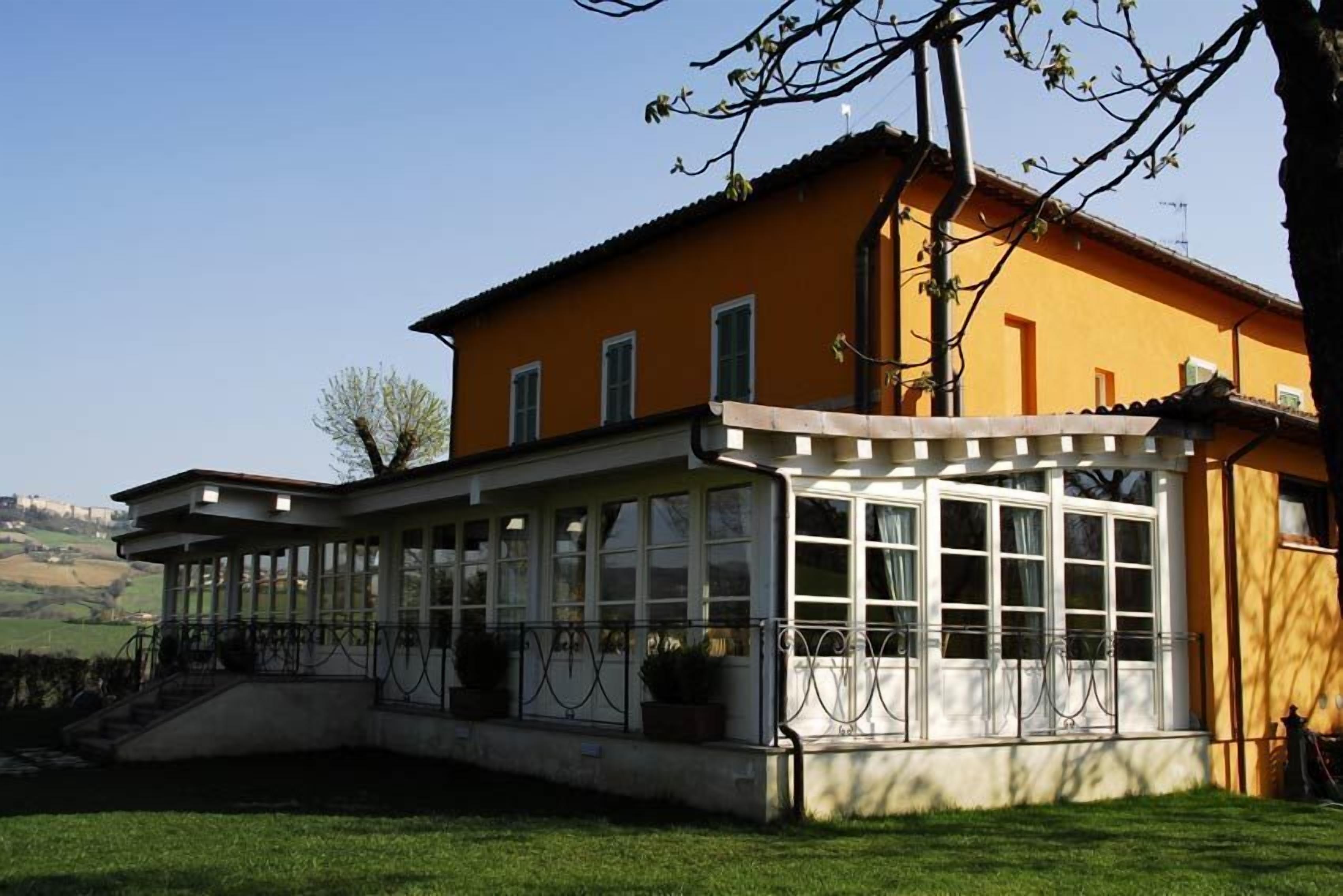 Ein gelbes Gebäude mit überdachter Terrasse und großen Fenstern.