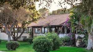 A house with a tiled roof, surrounded by lush greenery and a well-maintained lawn.
