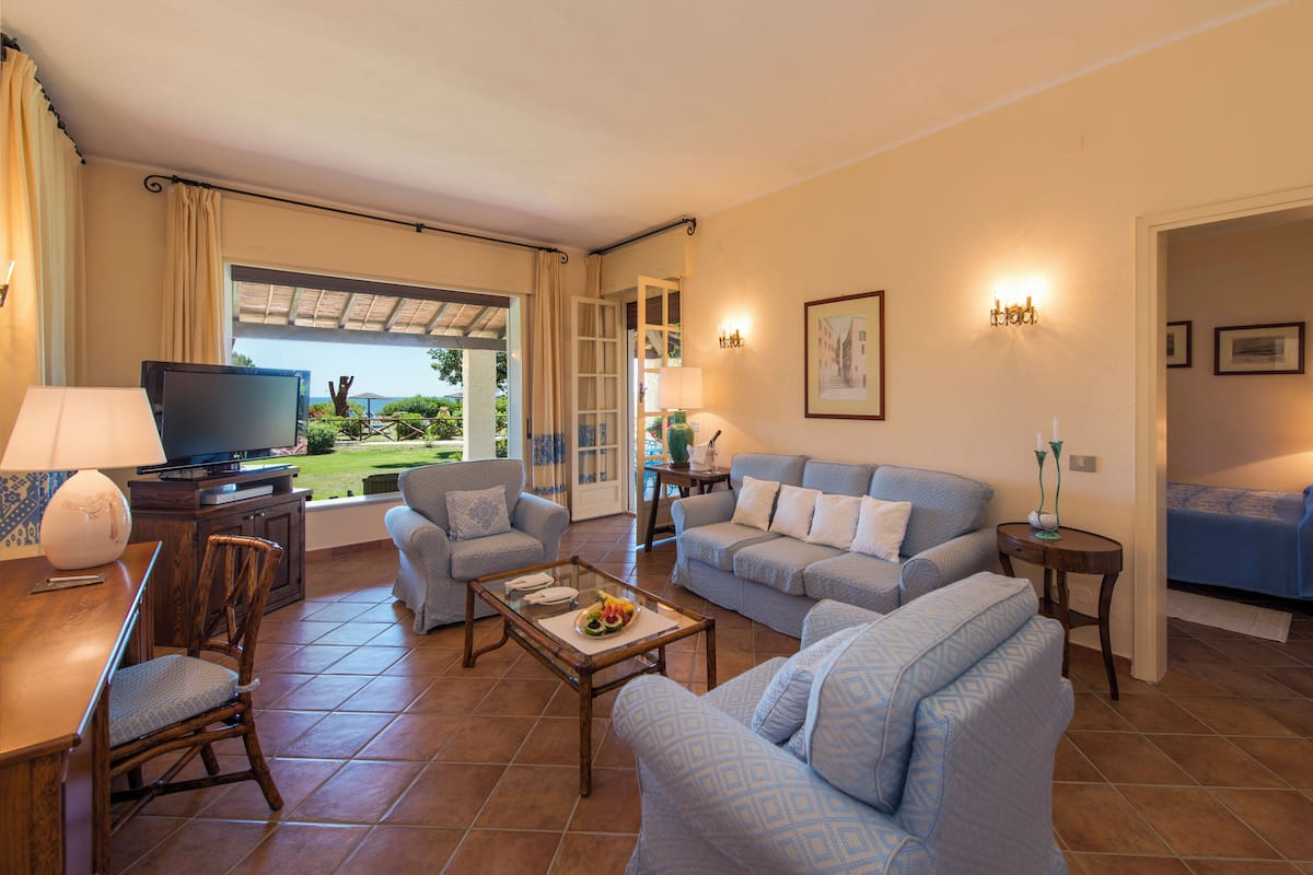 Una sala de estar con televisión, asientos y vistas al exterior.