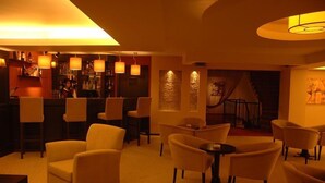 A warmly lit lounge area with multiple seating options, including sofas and chairs, and a bar area in the background. - Hotel Abro Necatibey (Ankara)