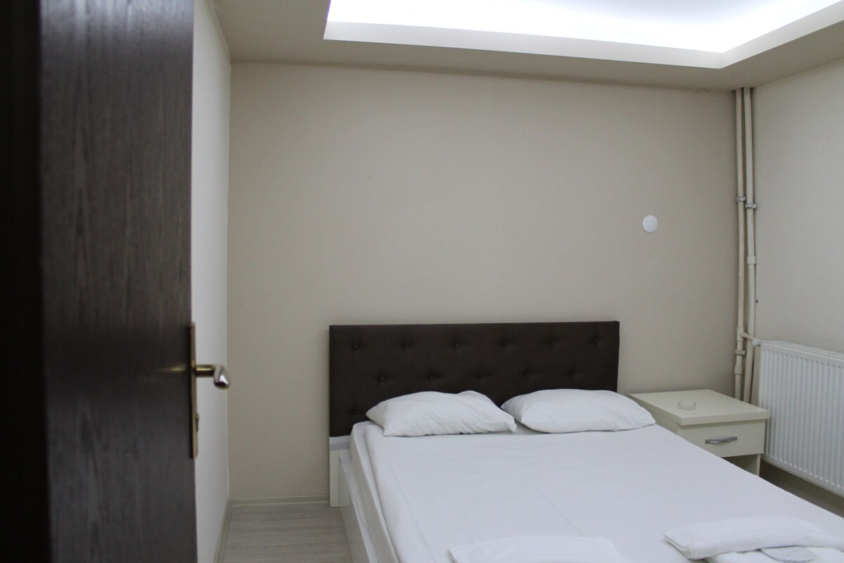 A bedroom with a bed, a nightstand, a drawer, and a skylight.