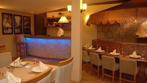 A restaurant with a bar area, wooden chairs, and tables set for dining. - Hotel Abro Necatibey (Ankara)