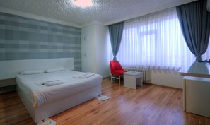 A modern hotel room with a large bed, a small desk, a red chair, and a window with sheer curtains. - Hotel Abro Necatibey (Ankara)