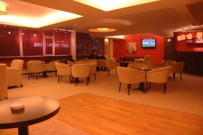 A hotel lobby with a red accent wall, multiple seating areas, and a television screen. - Hotel Abro Necatibey (Ankara)