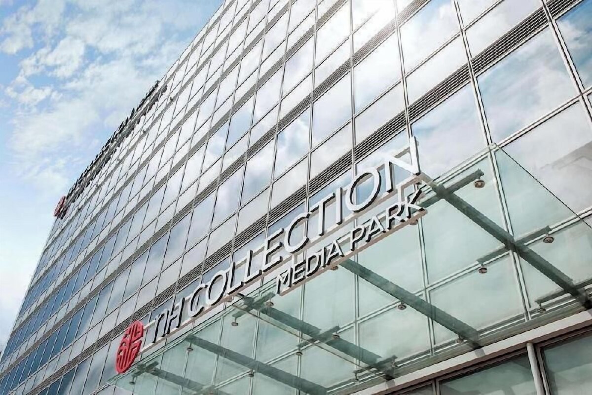 Un edificio moderno con fachada de vidrio y el texto 'THE COLLECTION MEDIA PARK' en el lateral.