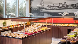 Un bufé con diferentes opciones de comida y un amplio ventanal con vista a la ciudad.