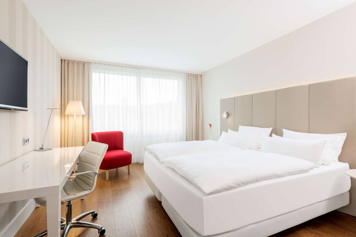 Ein Hotelzimmer mit Bett, Schreibtisch, Stuhl und Fernseher.