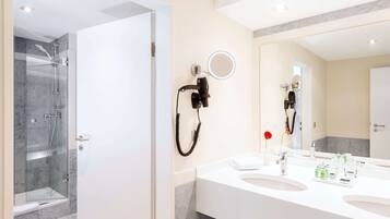 A modern bathroom with a glass shower enclosure, a vanity with two sinks, and a large mirror with a built-in light.