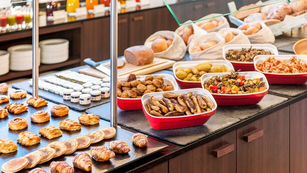 Un bufé con diversas opciones de comida, incluyendo pasteles, carnes y verduras.