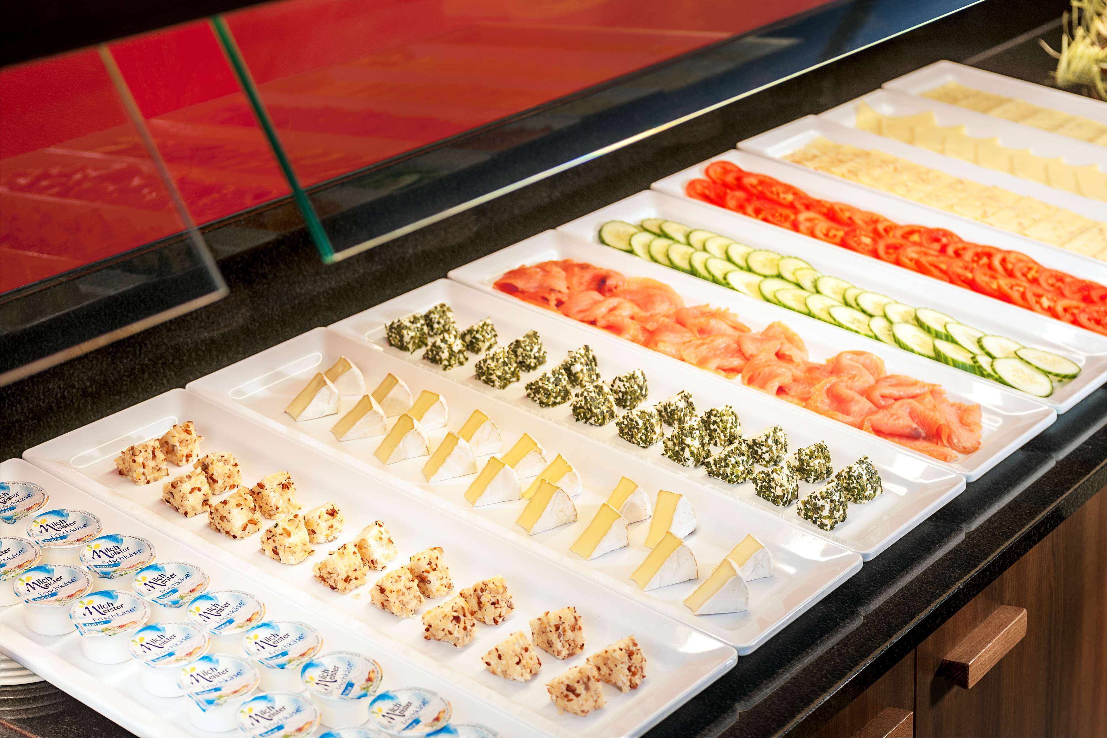 A buffet with various food items including salmon, cucumbers, and cheese.