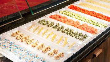 A buffet with various food items including salmon, cucumbers, and cheese.