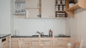 A kitchen with white cabinets, a sink, a coffee maker, and a shelf with jars. - Falken Hotel & Backpacker (Interlaken)