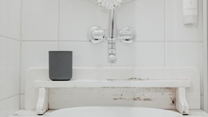 A bathroom with a white sink, a mirror above it, and a small black object on the counter. - Falken Hotel & Backpacker (Interlaken)