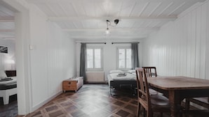 A room with a bed, a wooden chest, a table with chairs, and a window with curtains. - Falken Hotel & Backpacker (Interlaken)