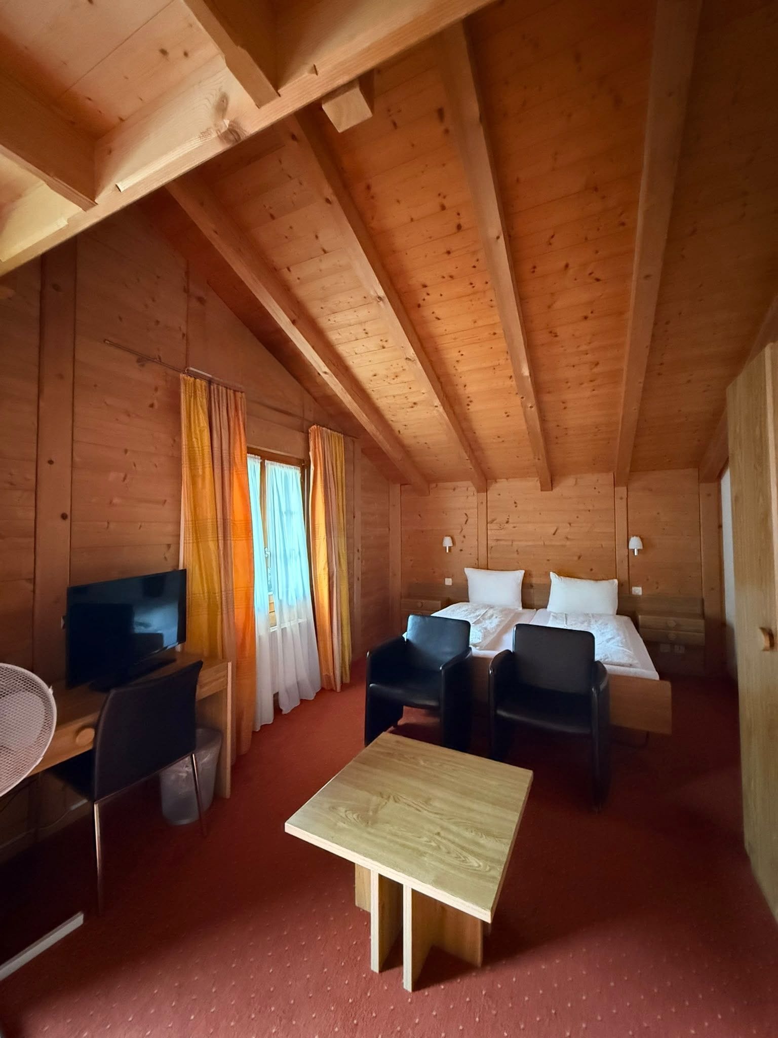 Una habitación cálida tipo cabaña con una cama, un escritorio y una silla.