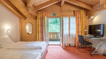 Habitación de hotel con cama, escritorio con computadora, televisor y vista al exterior.