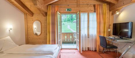 Habitación de hotel con cama, escritorio con computadora, televisor y vista al exterior.