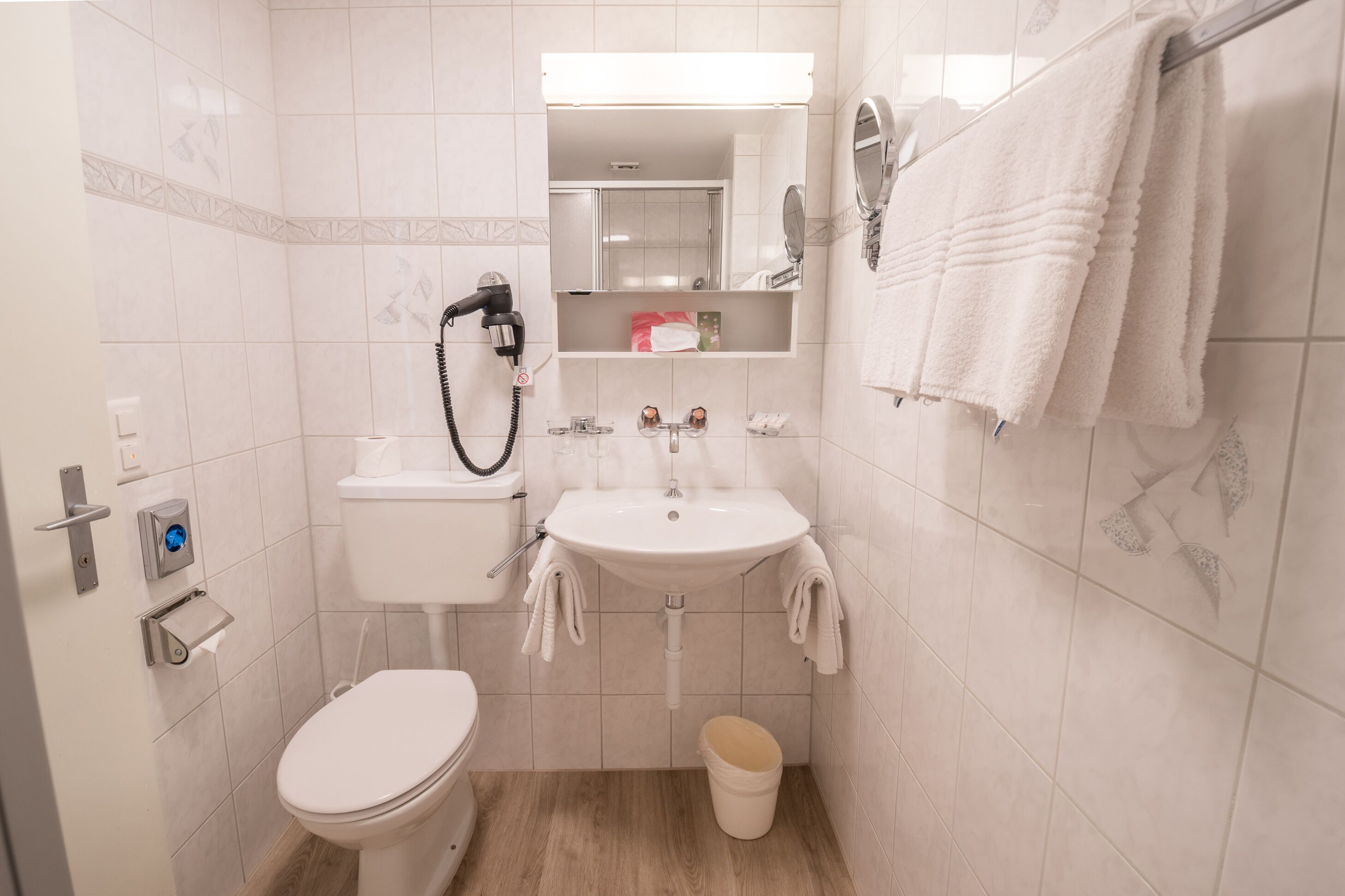 A compact bathroom with a toilet, sink, and hand dryer.