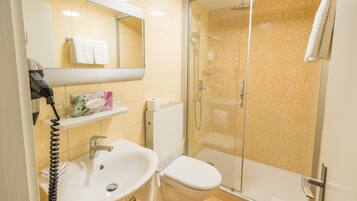 A bathroom with a sink, toilet, and glass-enclosed shower.