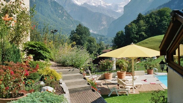 Une terrasse avec des sièges extérieurs, une piscine et une vue sur les montagnes.