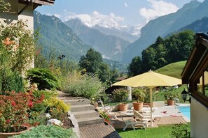 Een terras met buitenmeubilair, een zwembad en uitzicht op de bergen.