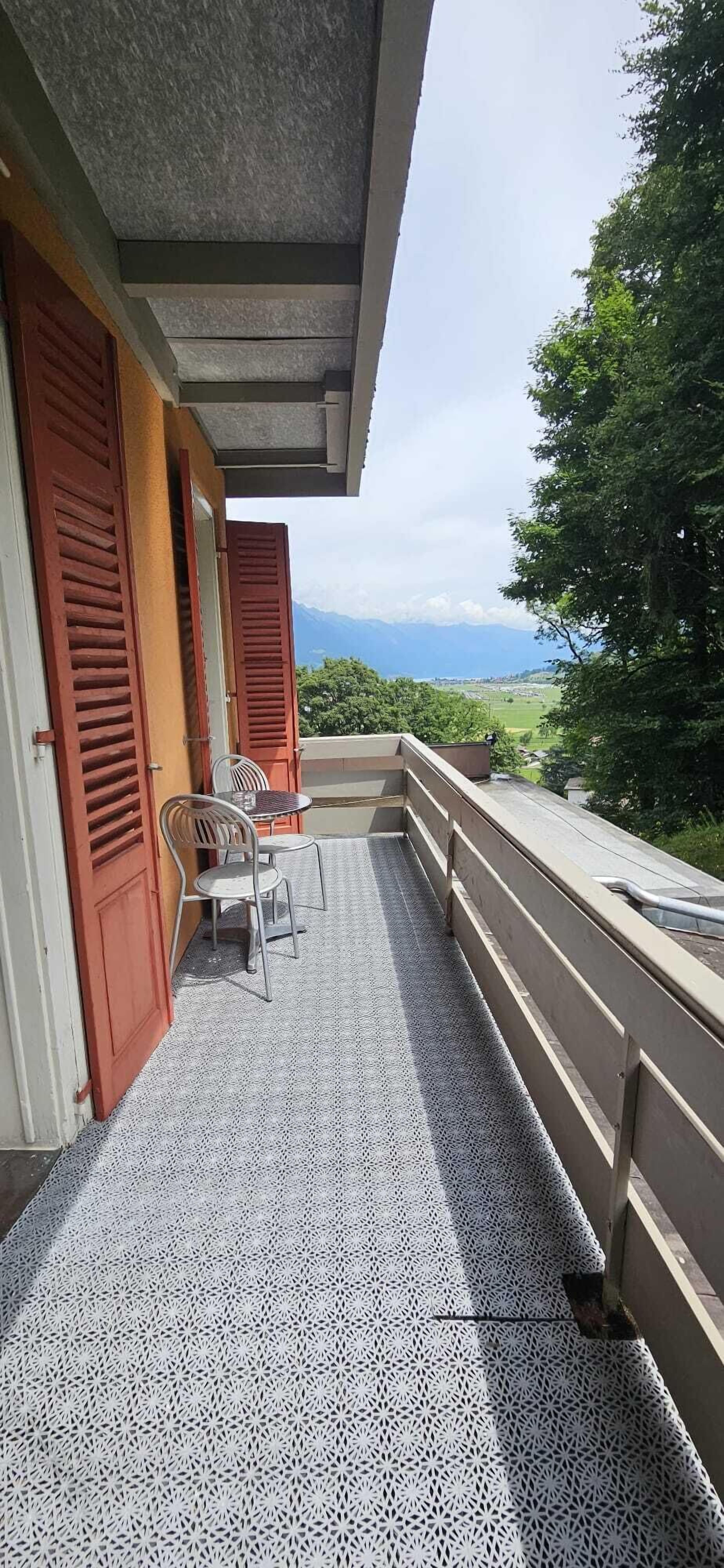 A balcony with a patterned floor, two chairs, and a table.