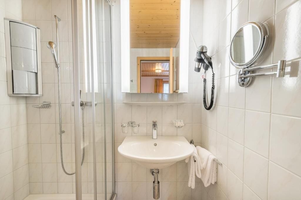 Une salle de bain avec une douche, un lavabo et un miroir.