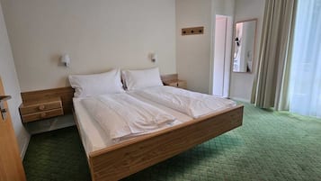 Ein Hotelzimmer mit einem hölzernen Bett, zwei Nachttischen, einem Spiegel und einem grünen Teppich.