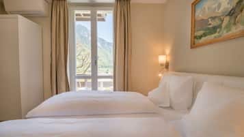 A hotel room with a bed, a painting on the wall, and a window with curtains.