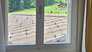 Une pièce dotée d’une grande fenêtre donnant sur un paysage verdoyant et un bâtiment.