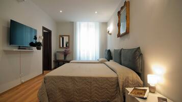 A hotel room with a large bed, a flat-screen TV, a bedside lamp, and a mirror on the wall.