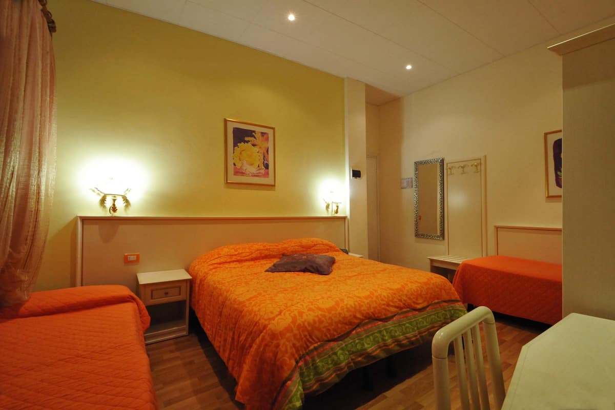 A hotel room with two single beds, a small table, a chair, and a mirror on the wall.