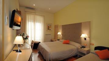 Una camera d'albergo con due letti, una scrivania con lampada, una TV e un quadro appeso al muro.