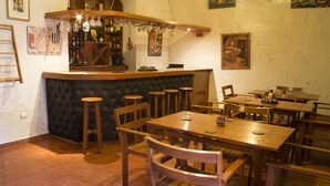 A restaurant with a bar area, wooden tables and chairs, and tiled flooring. - Posada Nueva España (Arequipa)