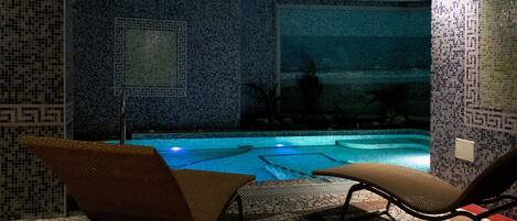 A pool area with mosaic tile walls and two lounge chairs facing the pool.