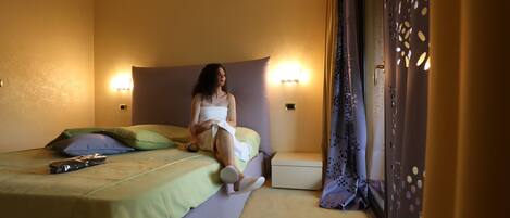 A room with a bed, a nightstand, and a wall-mounted lamp.