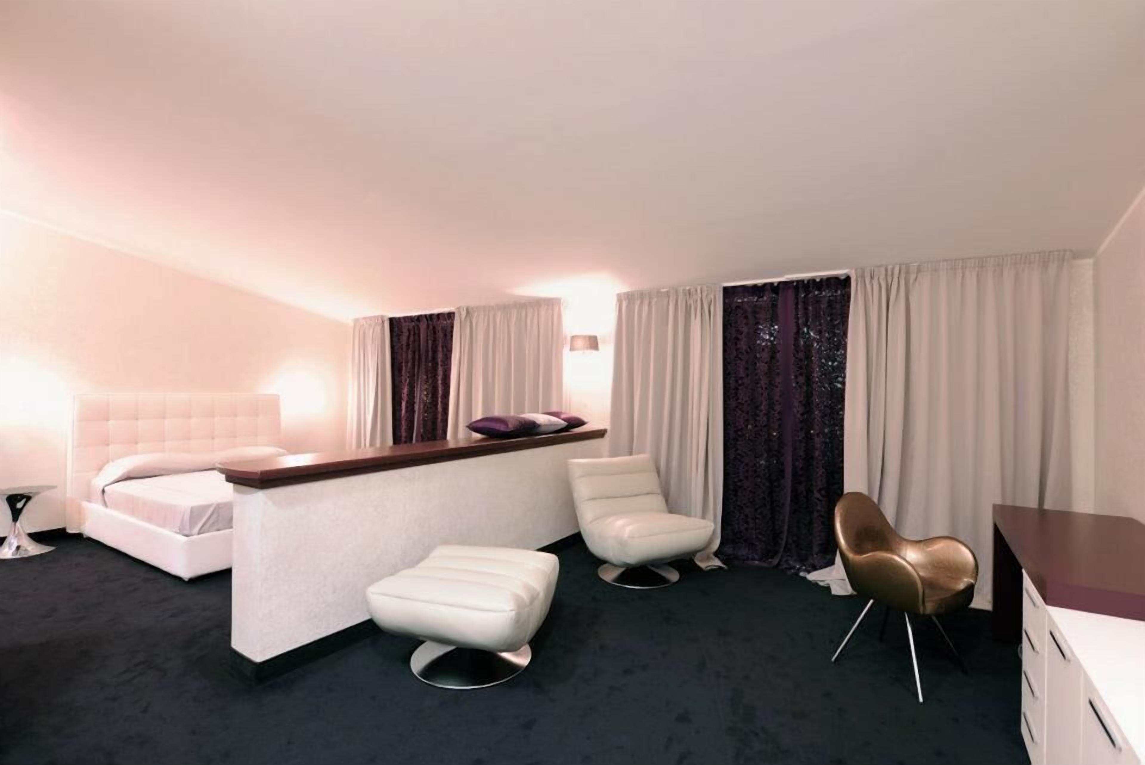 A hotel room with a bed, a desk, two chairs, and a small table.