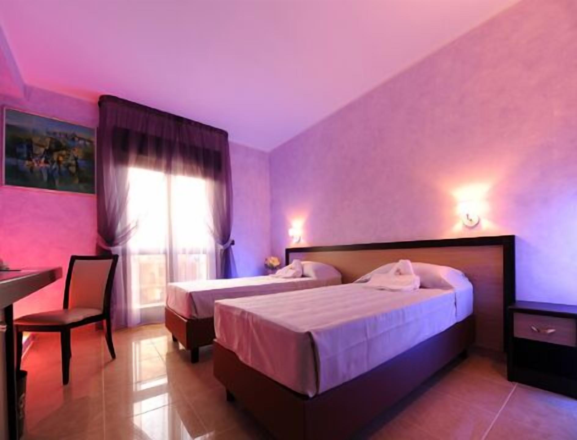 Una camera d'albergo con due letti, una scrivania e una sedia.