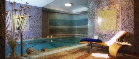 Un espacio de spa con piscina, una silla de descanso y un pilar decorativo.