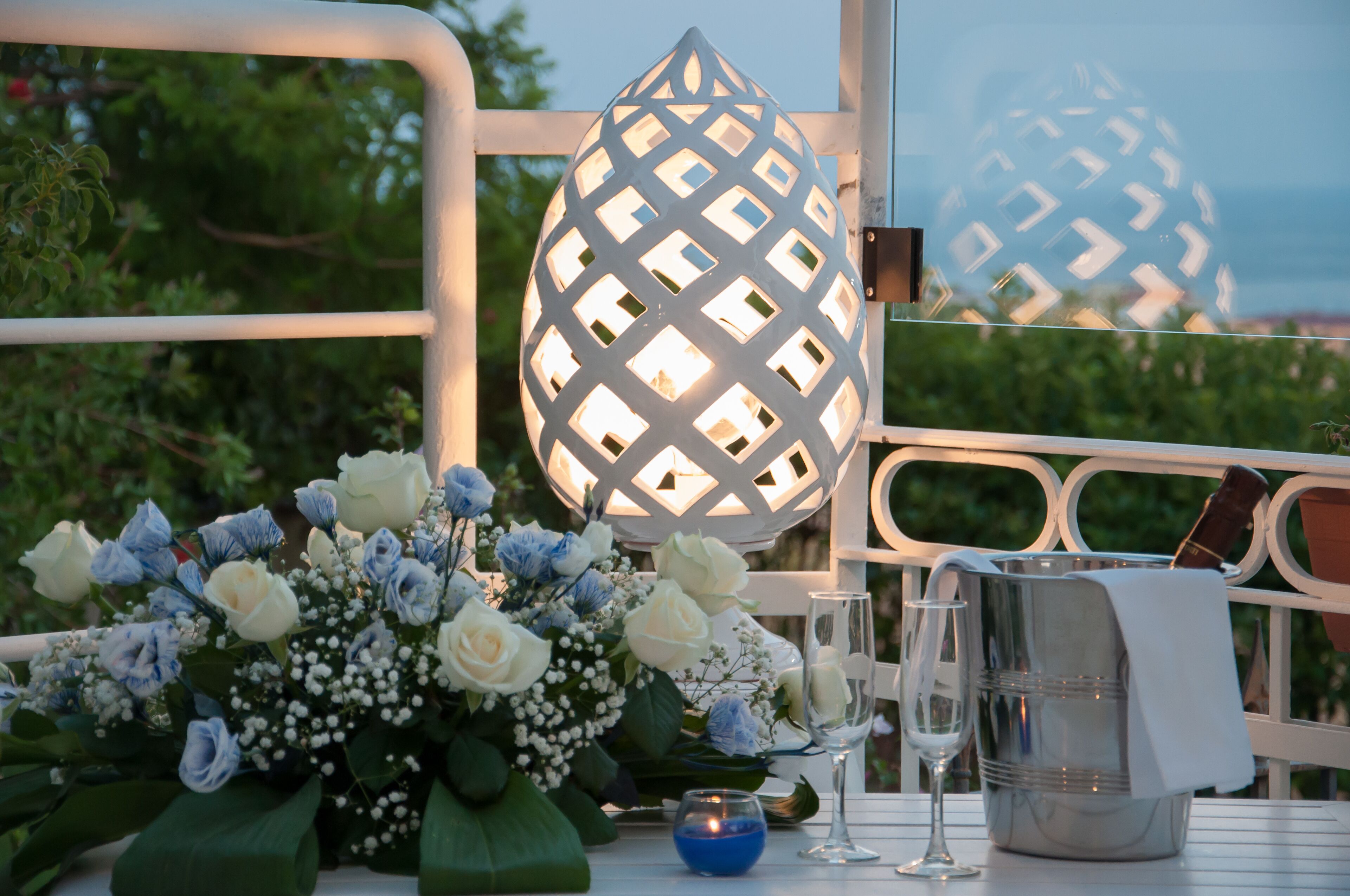 A table set with a floral arrangement, a candle, a glass, and a metal container.