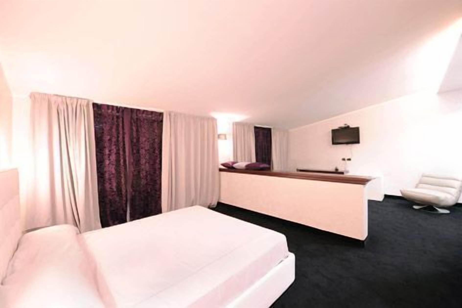Ein Hotelzimmer mit Bett, Schreibtisch, Stuhl und Fernseher.