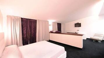 Ein Hotelzimmer mit Bett, Schreibtisch, Stuhl und Fernseher.