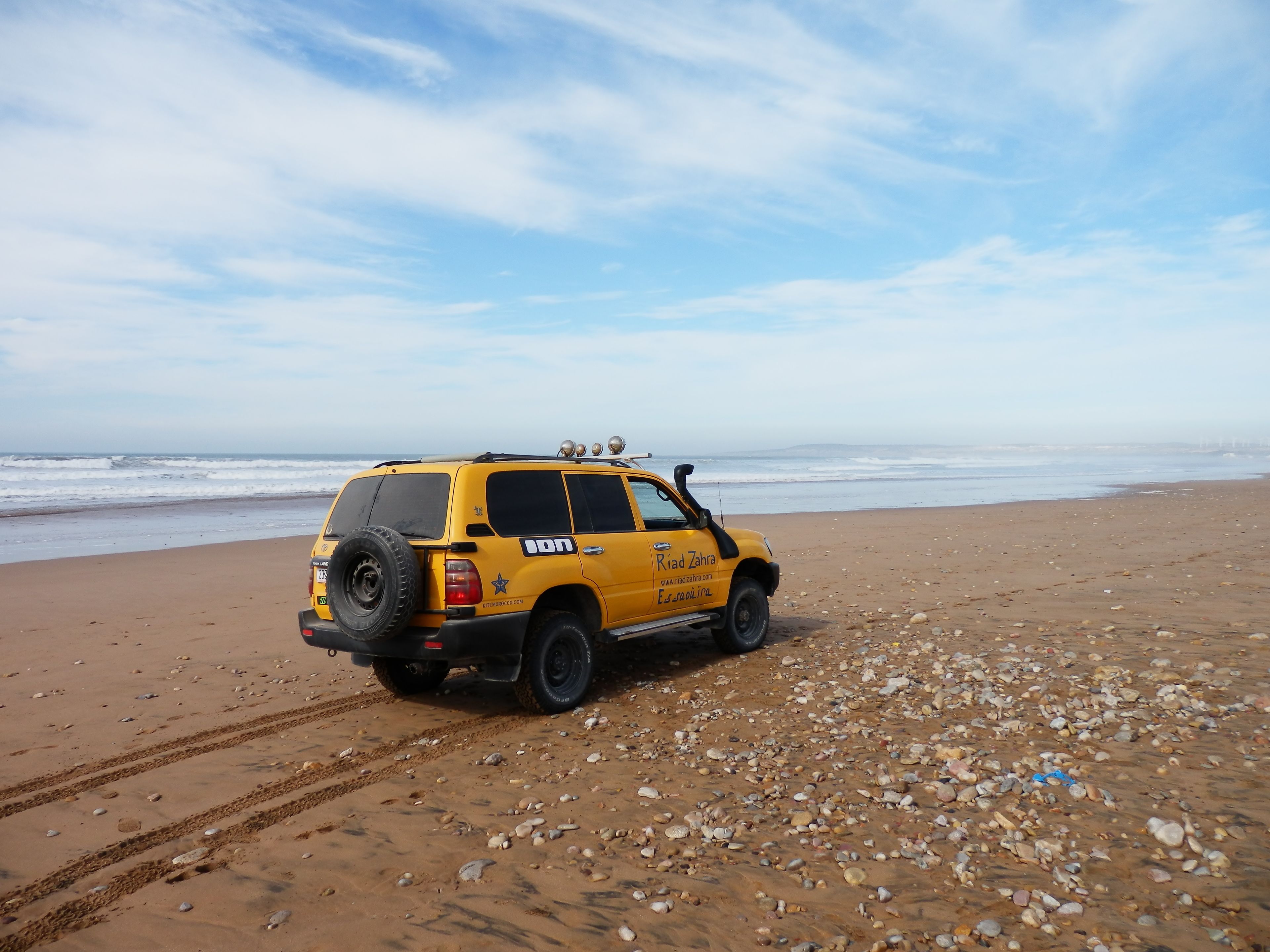 Rannalla, aurinkotuoleja, aurinkovarjoja, purjelautailumahdollisuus