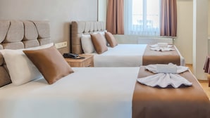 Habitación de hotel con dos camas, una mesita de noche de madera, un teléfono y una ventana con cortinas.