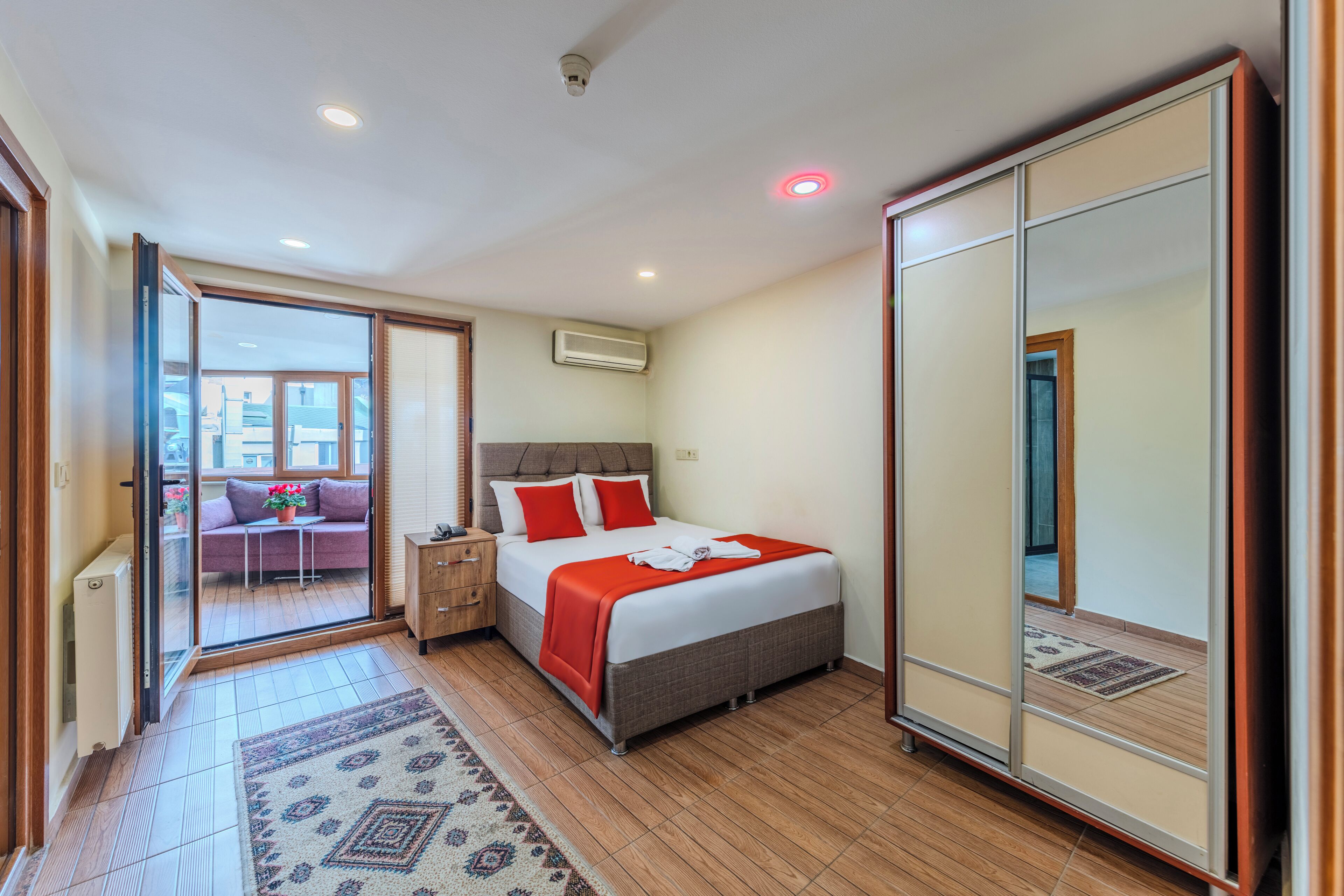 Une chambre d’hôtel moderne avec un grand lit, une armoire, une petite table et un canapé.