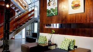Een moderne lobby met een trap, zithoek en kunstwerken aan de muur.