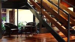 Een modern interieur met een spiltrap, houten vloeren en rieten meubilair.