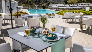 An outdoor dining area with tables and chairs, a pool in the background, and a view of the surrounding landscape. - Grande Hotel das Caldas da Felgueira (Nelas)